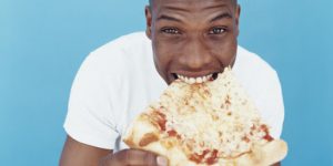 hombre comiendo una rebanada de pizza
