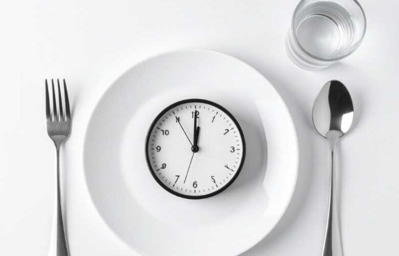 plato y cubiertos con un reloj representando el ayuno intermitente