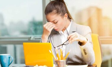 mujer frente a una computadora en su oficina sintiendo cansancio extremo